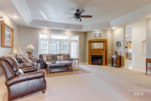 1795 W Black Canyon Hwy, Emmett, ID 83617 - living room featuring ceiling fan, a raised ceiling, baseboards, a glass covered fireplace, and carpet flooring