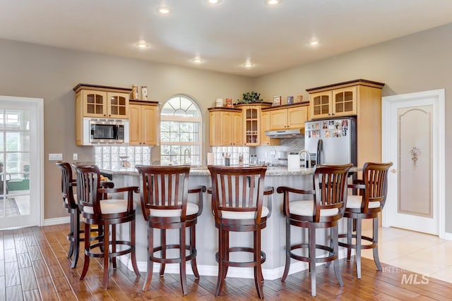 1795 W Black Canyon Hwy, Emmett, ID 83617 - kitchen featuring light wood-style floors, appliances with stainless steel finishes, tasteful backsplash, glass insert cabinets, and under cabinet range hood