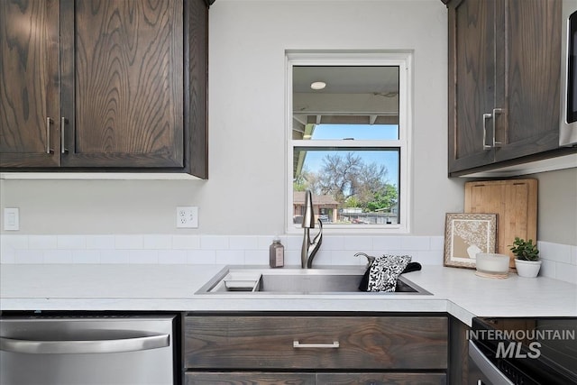 kitchen with stainless steel dishwasher, a sink, dark brown cabinetry, and light countertops