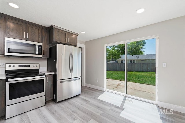 kitchen featuring light countertops, dark brown cabinetry, appliances with stainless steel finishes, and light wood-type flooring