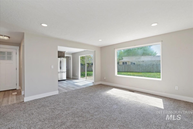 spare room featuring baseboards, visible vents, recessed lighting, and light colored carpet
