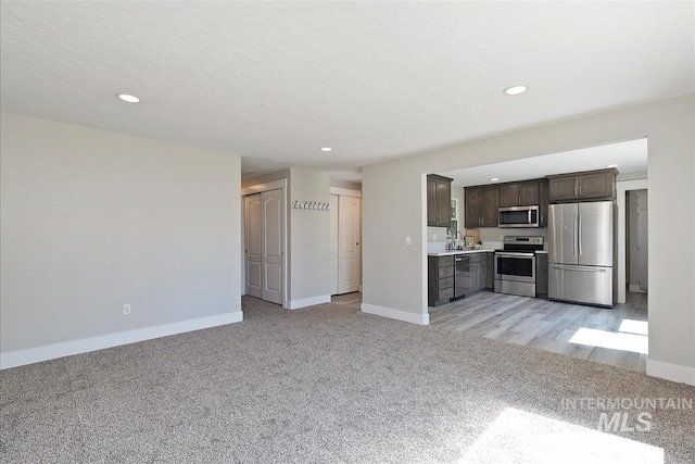 unfurnished living room featuring baseboards, light carpet, and recessed lighting