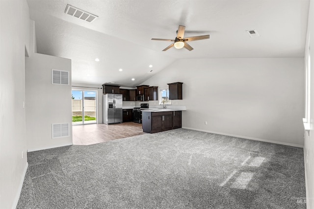 kitchen featuring appliances with stainless steel finishes, open floor plan, light countertops, lofted ceiling, and a ceiling fan