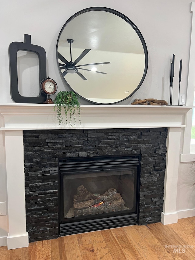 details featuring ceiling fan, hardwood / wood-style flooring, and a stone fireplace