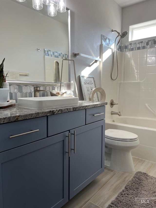 full bathroom with shower / bath combination, wood-type flooring, toilet, and vanity