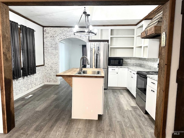 kitchen with appliances with stainless steel finishes, brick wall, a center island with sink, decorative light fixtures, and white cabinets