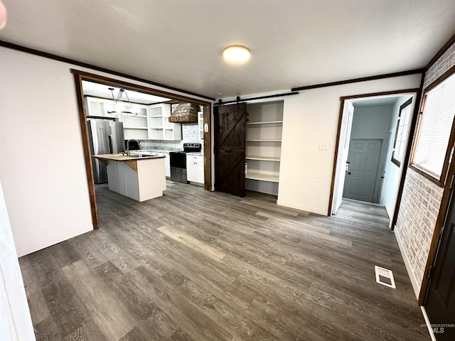 kitchen with sink, a barn door, range with electric stovetop, a kitchen island, and stainless steel refrigerator