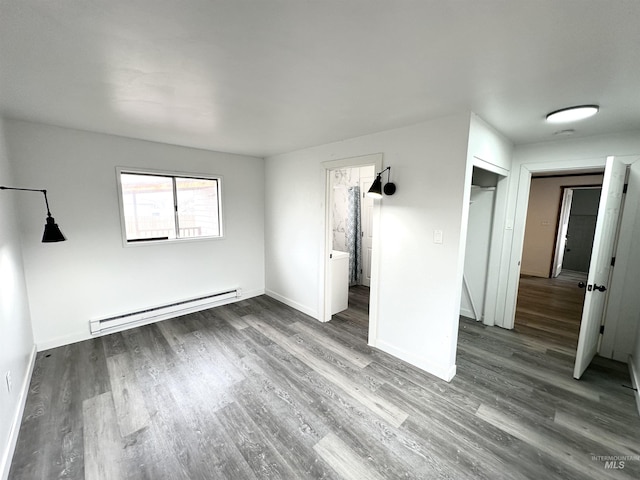 unfurnished bedroom featuring dark hardwood / wood-style flooring, connected bathroom, and a baseboard heating unit