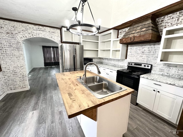 kitchen featuring sink, wood counters, decorative light fixtures, a center island with sink, and appliances with stainless steel finishes