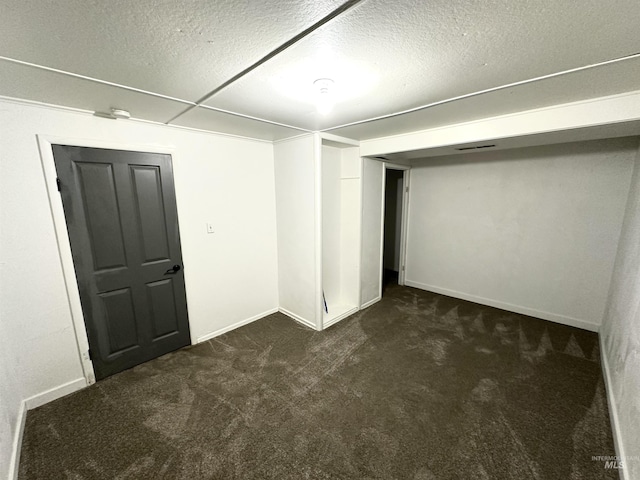 basement featuring a textured ceiling and dark carpet