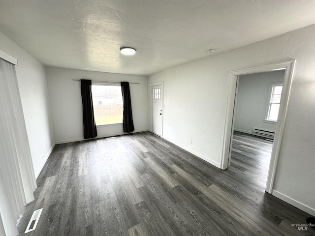 spare room with dark hardwood / wood-style flooring and a baseboard heating unit