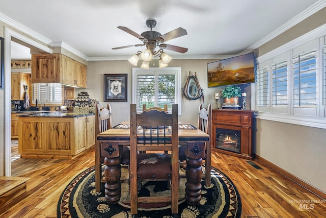 dining area featuring light wood-type flooring, ornamental molding, and plenty of natural light