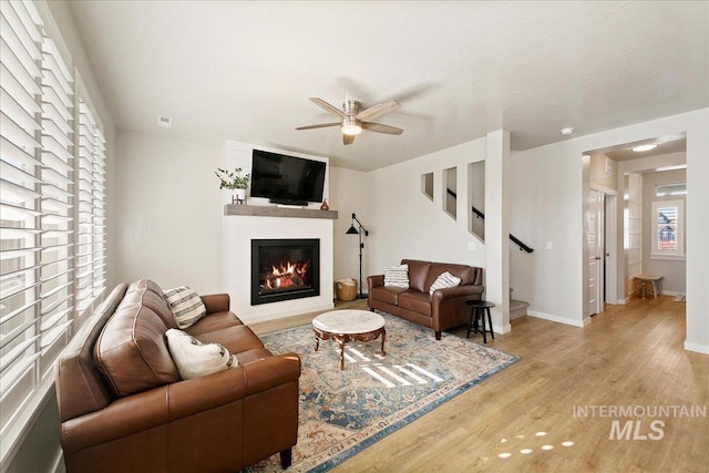 living room with ceiling fan, light hardwood / wood-style flooring, and a fireplace