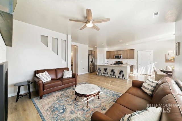 living room featuring light wood-type flooring and ceiling fan