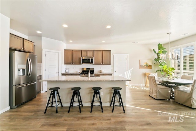 kitchen featuring sink, a kitchen island with sink, hanging light fixtures, and stainless steel appliances