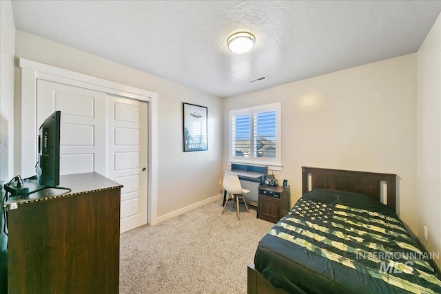 bedroom with a closet, light colored carpet, and a textured ceiling