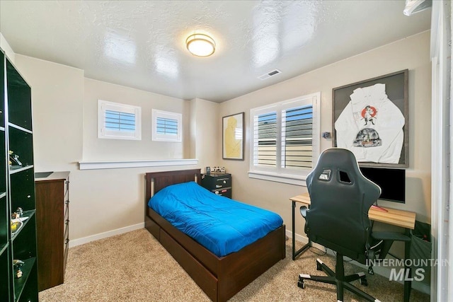 bedroom with light colored carpet and a textured ceiling