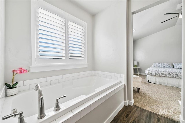 bathroom with ceiling fan, wood-type flooring, tiled bath, and lofted ceiling