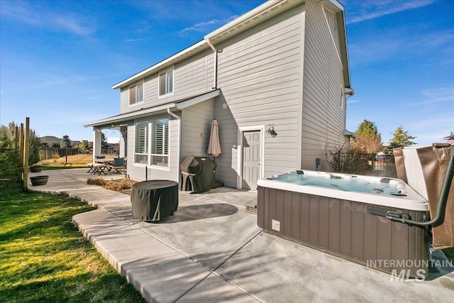 rear view of house featuring a patio and a hot tub