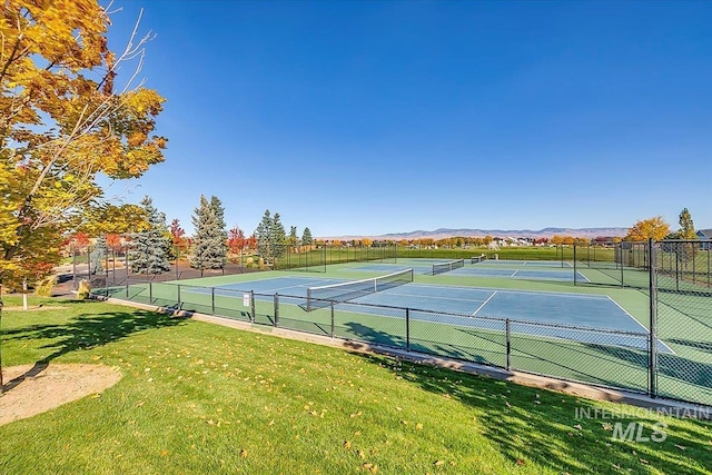 view of tennis court with a mountain view and a lawn