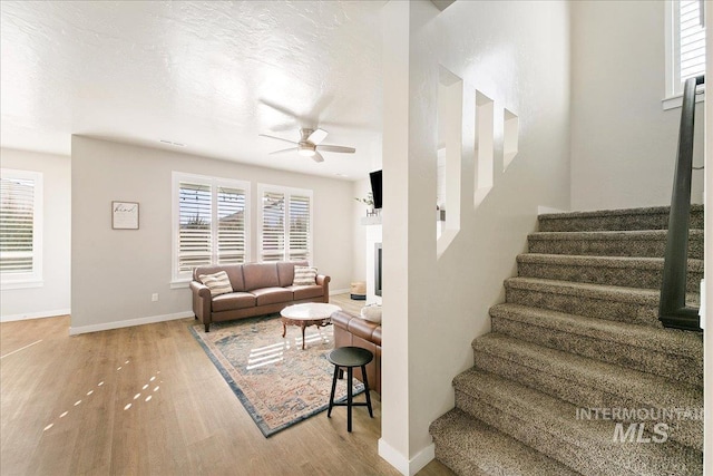 stairs featuring wood-type flooring, a textured ceiling, and ceiling fan