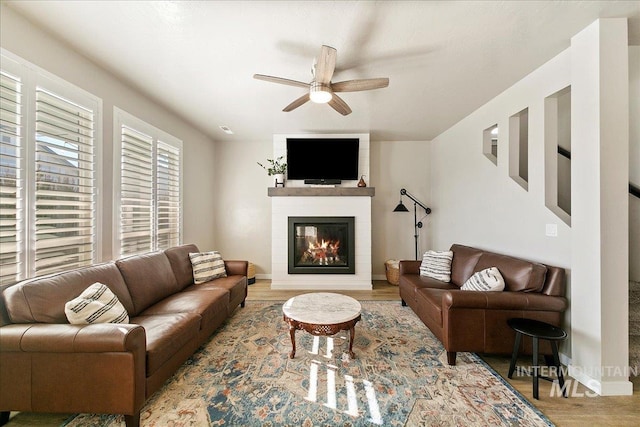 living room with a fireplace, light hardwood / wood-style flooring, and ceiling fan