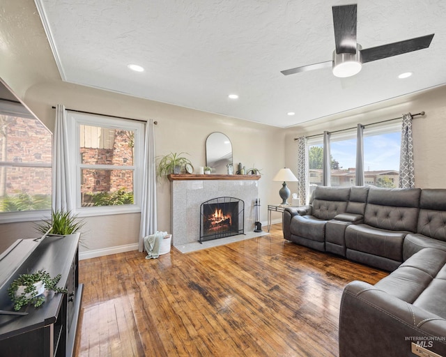 209 N Canyon St, Nampa, ID 83651 - living room featuring wood-type flooring, a fireplace with flush hearth, baseboards, a textured ceiling, and ceiling fan