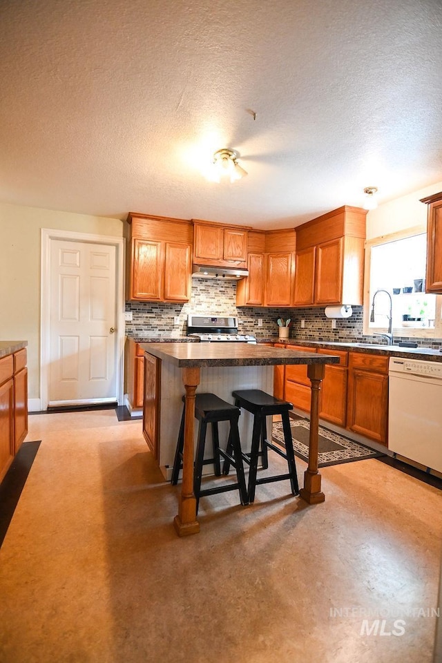 221 N Union St, Star, ID 83669 - kitchen featuring dishwasher, under cabinet range hood, stainless steel range, decorative backsplash, and a breakfast bar area