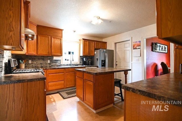 221 N Union St, Star, ID 83669 - kitchen featuring stainless steel appliances, decorative backsplash, a breakfast bar area, dark countertops, and a textured ceiling