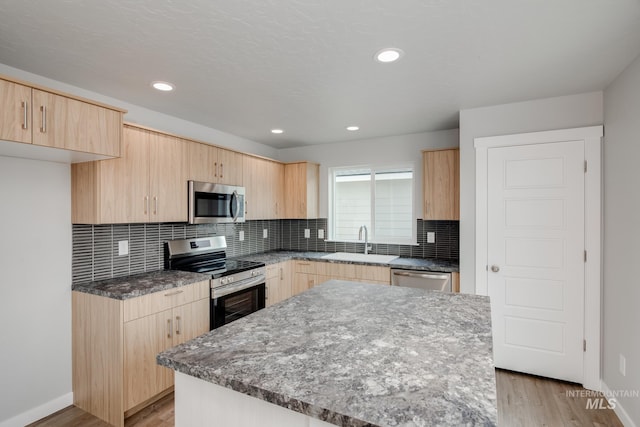 kitchen with a center island, stainless steel appliances, light brown cabinetry, and sink