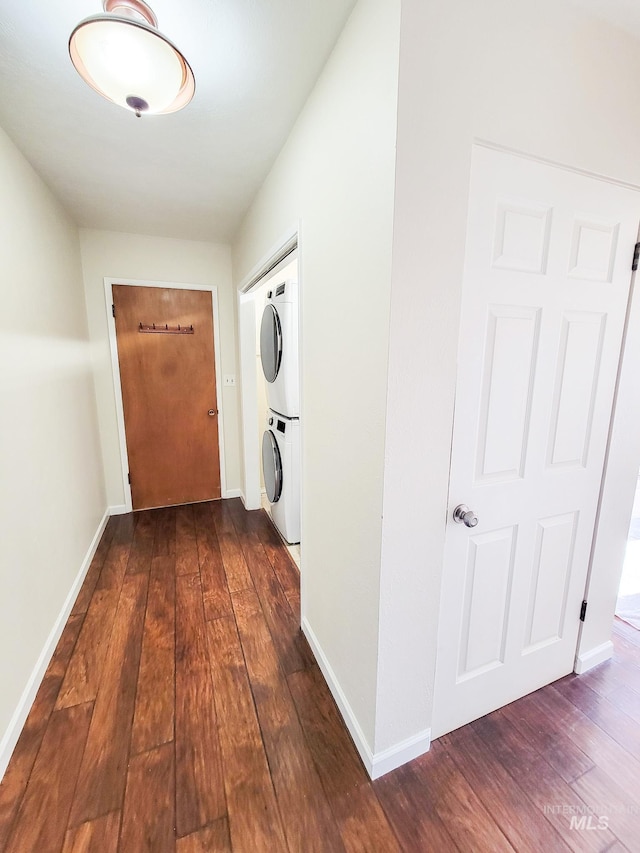 corridor featuring stacked washer and clothes dryer and dark hardwood / wood-style floors