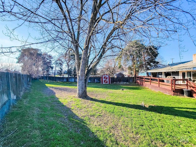 view of yard featuring a wooden deck and a storage shed