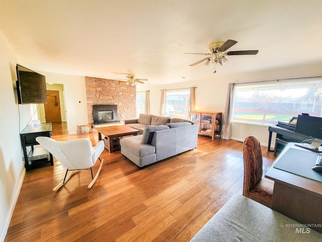 living room with ceiling fan, a fireplace, and light hardwood / wood-style flooring