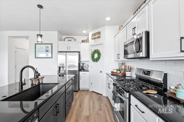 1499 W Blue Downs St, Meridian, ID 83642 - kitchen with appliances with stainless steel finishes, a sink, white cabinets, hanging light fixtures, and light wood-type flooring
