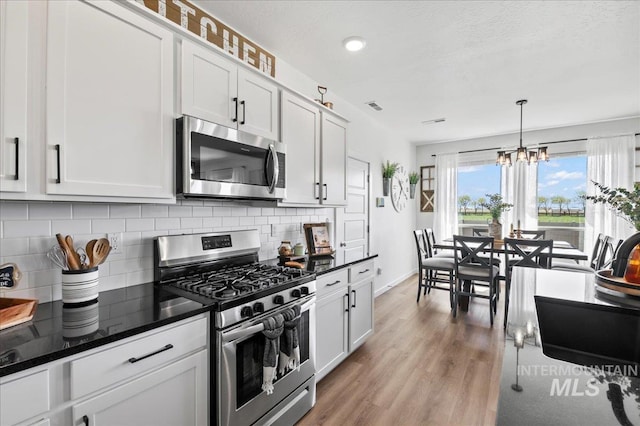 1499 W Blue Downs St, Meridian, ID 83642 - kitchen featuring appliances with stainless steel finishes, backsplash, a chandelier, light wood finished floors, and baseboards