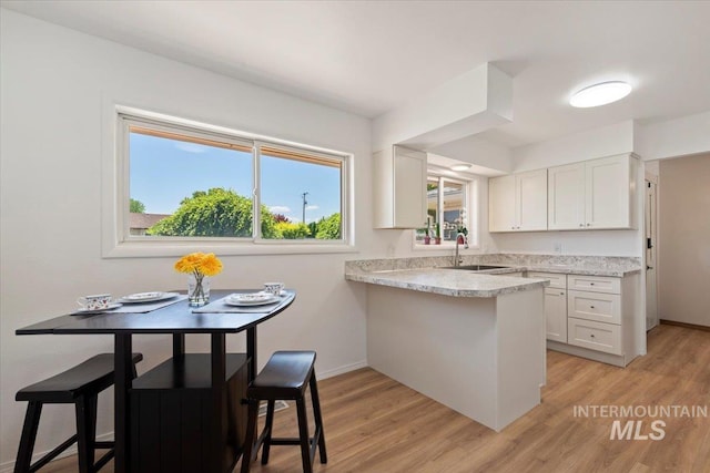 611 E Dewey Ln, Caldwell, ID 83607 - kitchen with white cabinetry, a peninsula, light wood-type flooring, and light stone counters