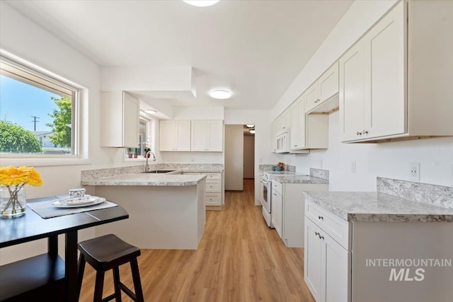 611 E Dewey Ln, Caldwell, ID 83607 - kitchen featuring white appliances, light wood-type flooring, light countertops, white cabinets, and a peninsula