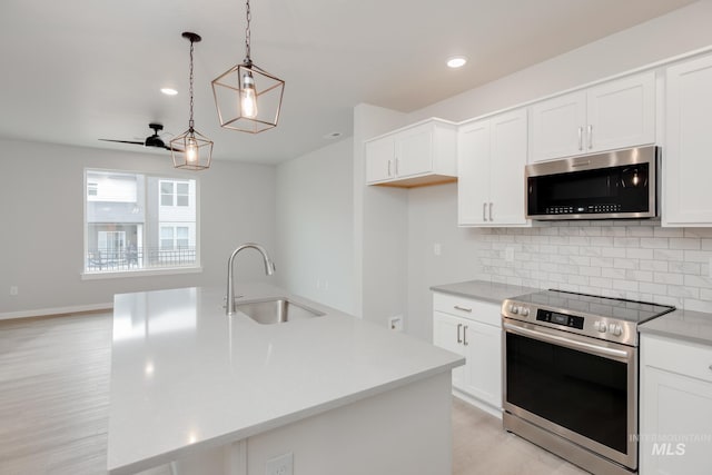 kitchen featuring a sink, light wood-type flooring, backsplash, white cabinetry, and appliances with stainless steel finishes
