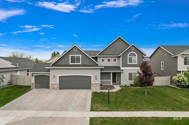 craftsman inspired home featuring fence, stone siding, a front yard, board and batten siding, and driveway