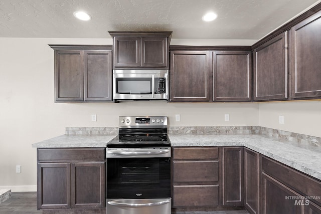 kitchen featuring wood finished floors, light countertops, dark brown cabinetry, and stainless steel appliances