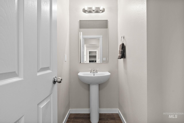 bathroom featuring baseboards, a sink, and wood finished floors