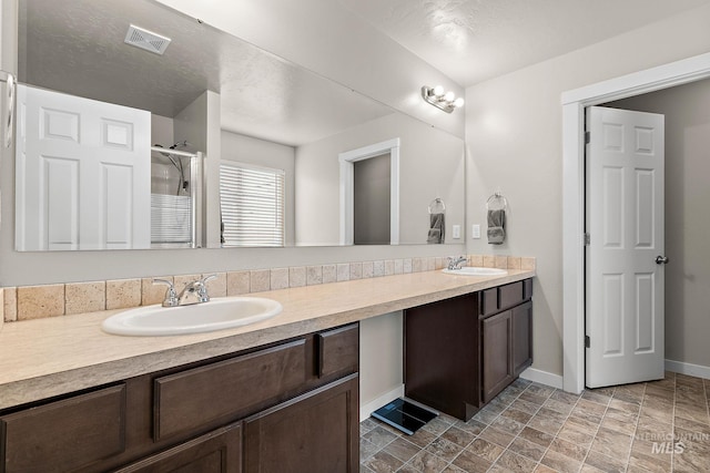 bathroom featuring a sink, baseboards, double vanity, and visible vents
