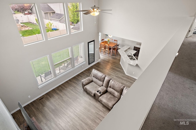 living room featuring a healthy amount of sunlight, a high ceiling, a ceiling fan, and wood finished floors
