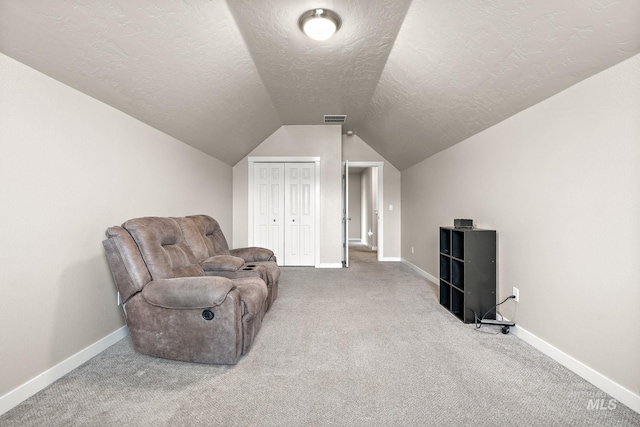 sitting room with a textured ceiling, visible vents, baseboards, carpet floors, and lofted ceiling