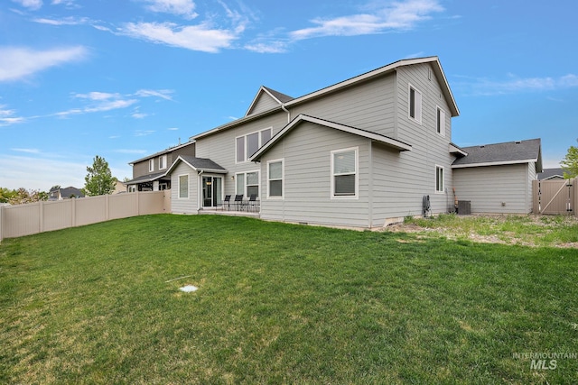 rear view of house featuring fence, a gate, a yard, and central AC