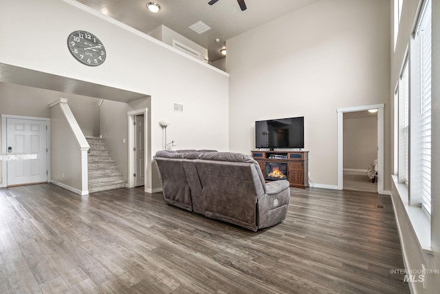 living area featuring visible vents, ceiling fan, a high ceiling, and dark wood-style floors