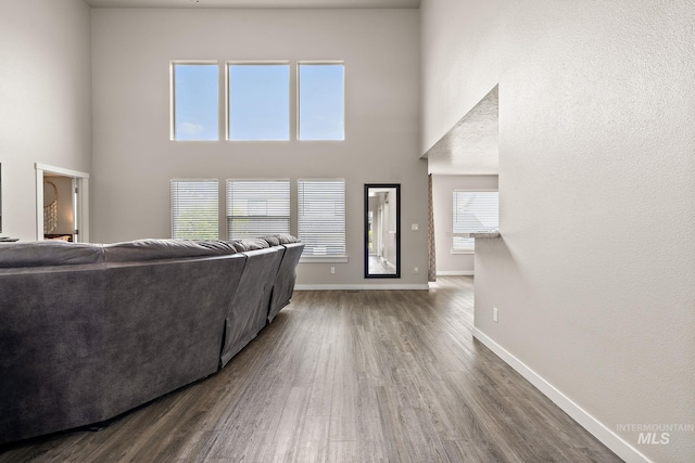 living room featuring baseboards, a high ceiling, and wood finished floors