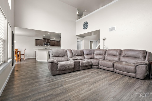 living room with visible vents, a towering ceiling, dark wood-type flooring, and baseboards