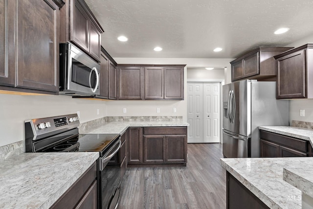 kitchen with wood finished floors, light countertops, appliances with stainless steel finishes, and dark brown cabinetry