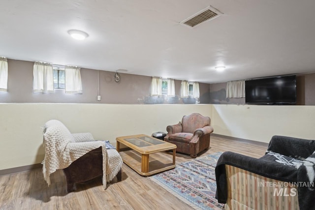 living room with light wood-type flooring, visible vents, and baseboards